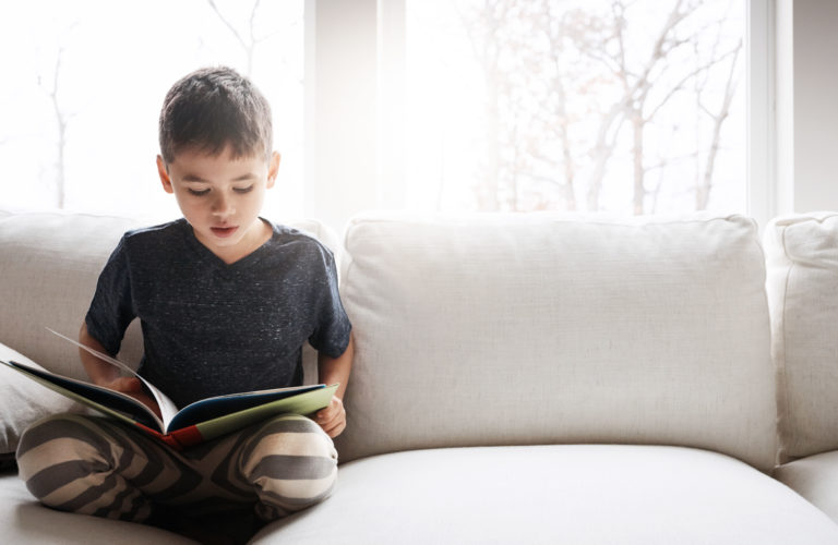 Child reading a book on a couch